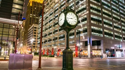 Historic clock on the corner of an intersection in downtown Houston at night.