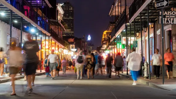 People walking down Bourbon Street in New Orleans at night.