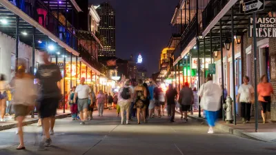 People walking down Bourbon Street in New Orleans at night.