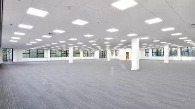 Large empty office building floor with white walls and grey carpeting