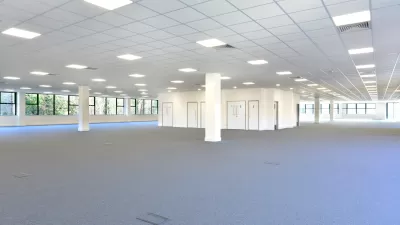 Empty open plan office with gray carpet and white walls