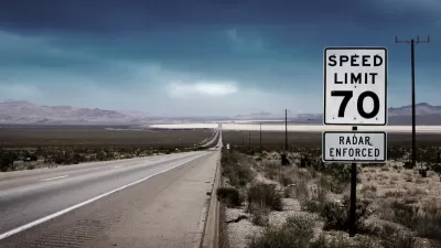 70 mph speed limit sign with bullet holes on southwestern highway with desert mountains in background.