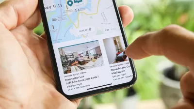 Close-up of hand holding phone with AIrbnb app open to New York City listings
