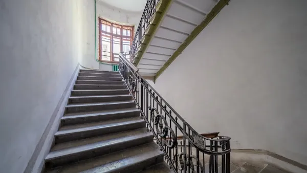 Wide apartment building staircase with curved wrought iron handrail.