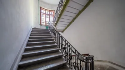 Wide apartment building staircase with curved wrought iron handrail.