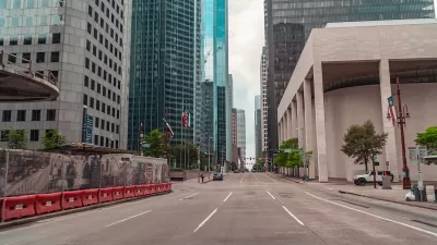 Large brutalist building and skyscrapers viewed from middle of wide street in downtown Houston, Texas.