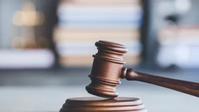 A wooden gavel with gray background filled with a stack of books.