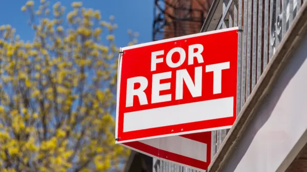 Close-up on red and white "For Rent" sign on building.