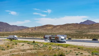 View of trucks on Interstate 15 with desert mountains in background in Southern California.