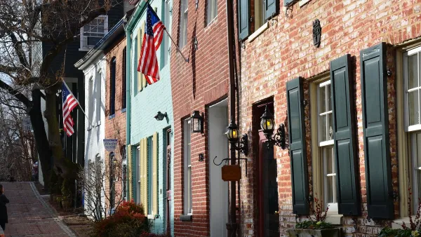 Row of colorful two-story brick residential buildings in Washington, D.C. with U.S. flags hanging from doorways.