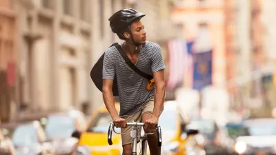 Man riding bicycle wearing black helmet on New York City street.