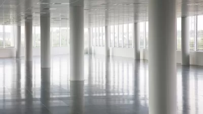 White round pillars in empty office building with windows across all walls and white floors and ceiling.