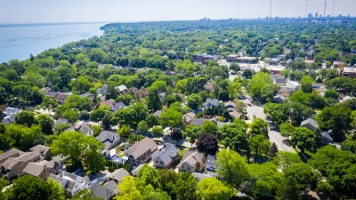 Aerial view of large homes surrounded by mature trees with Lake MIchigan shoreline at left.