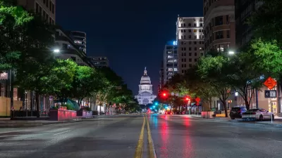 Low angle view of Texas state capitol at night from middle of wide street.