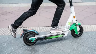 Close-up of person riding green and white Lime e-scooter.