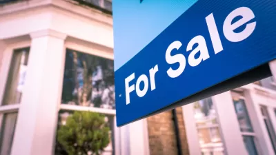 Close-up of blue For Sale sign in front of house.