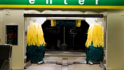 Entrance to a drive-through car wash at night with green 'Enter' sign.