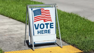 "Vote Here" sandwich board sign with American flag on sidewalk in Fort Lauderdale, Florida.