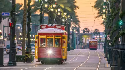 Red and yellow New Orleans streetcar running down street lined with palm trees