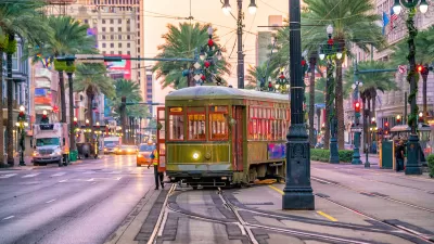 Historic streetcar in middle of street in downtown New Orleans, Louisiana with palm trees and historic lampposts lining the street.