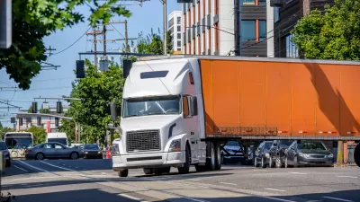 Orange big rig truck turning on a city street
