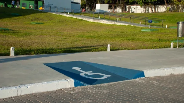 Blue sidewalk curb cut painted with white accessibility symbol.