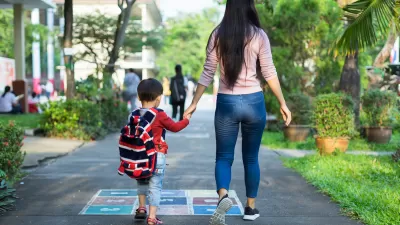View from back of mother and hcild holding hands and walking down asphalt walkway painted with game grid.