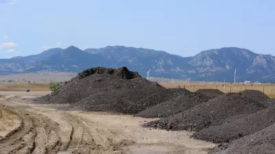 Piles of recycled asphalt and bitumen to be recycled for making roads with Rocky Mountains in background.