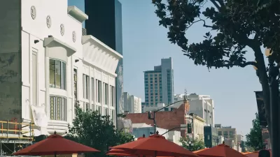 The tops of umbrellas for outdoor dining spaces are visible with large buildings in the background on a sunny day in the city of San Diego.