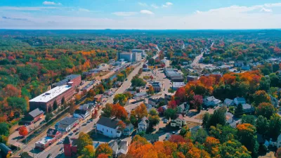 Aerial view of small New Hampshire town with brick buildings and fall foliage.