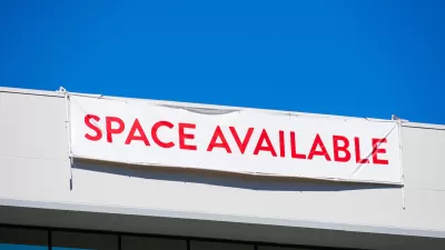 White banner with red "SPACE AVAILABLE" text hanging at top of white office building.