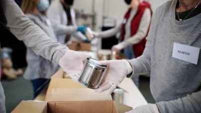 Close-up of people wearing white gloves and Covid-19 masks exchanging unlabeled can of food at food bank