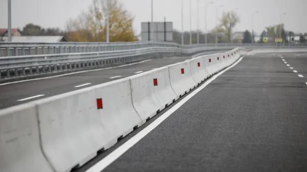 Row of concrete Jersey barriers running down the middle of a multi-lane road.