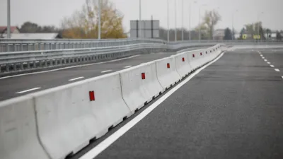 Row of concrete Jersey barriers running down the middle of a multi-lane road.