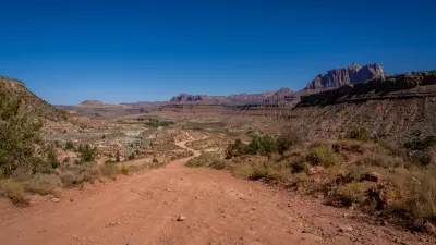 Dirt road on BLM land in Utah near Zion National Park with red cliff formations in background.