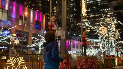 Child looking up at Christmas lights in city at night.