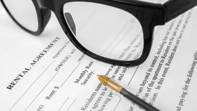 Close-up of rental agreement with pen and black-rimmed glasses.
