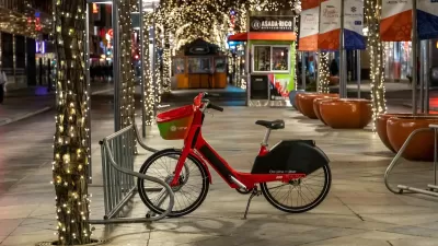 Lime rental bike on sidewalk in Denver, Colorado with Christmas lights in background.