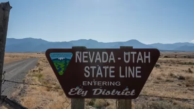 Roadside sign for Nevada Utah State Line "Entering Ely District" with Bureau of Land Management logo with desert mountains in background.