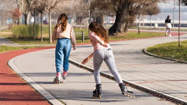 Two young women roller skating in a park on a sunny day.