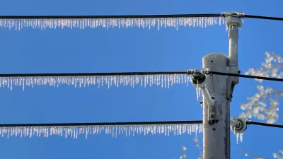 Power lines with dense icicles hanging from them against blue sky.