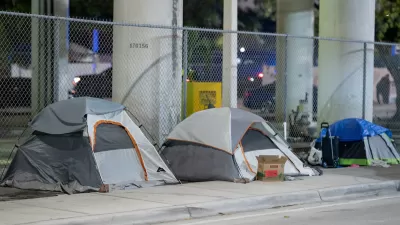 Three small tents set up on sidewalk under overpass in Miami, Florida.