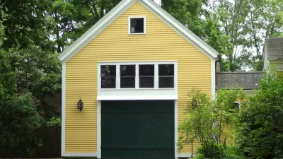 Yellow converted garage with green door and white-framed windows.