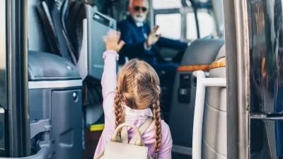 Young girl with pigtail braids boarding bus with blurred bus driver in driver's seat in background