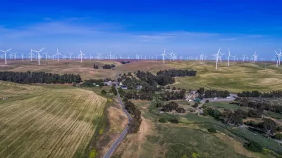 Aerial view of small community among green agricultural fields and wind turbines in Solano County, Northern California.