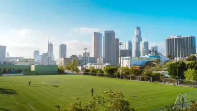 Green grass soccer field with Los Angeles skyline in background.