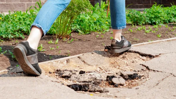 Person stepping over hole in sidewalk.