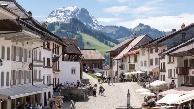 View of pedestrian plaza in Swiss village with Alps in background.