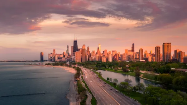 Aerial view of Lake Shore Drive, eight-lane highway adjacent to lakeshore in Chicago, Illinois with city skyline in background at sunset.