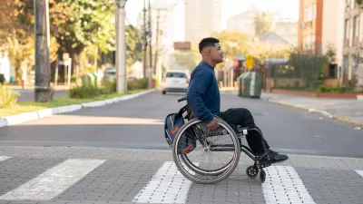 Young man in wheelchair crossing zebra crosswalk.